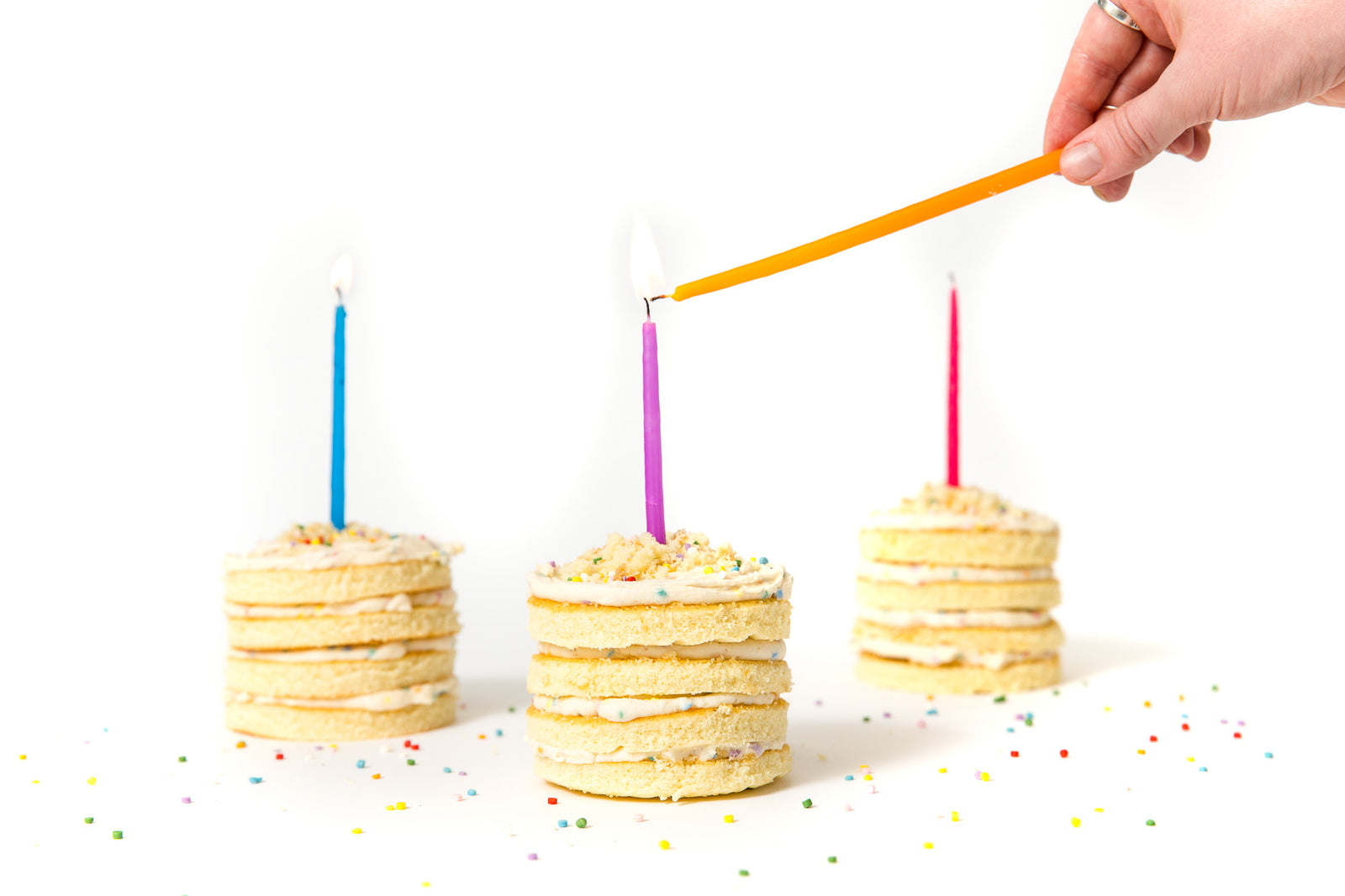 Image of side of three Miss Jones Baking Co Confetti Pop Mini Cakes with candles